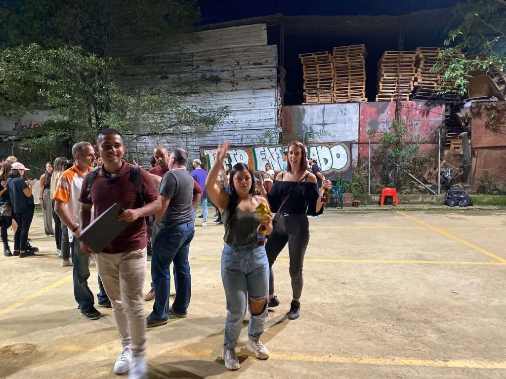 People socializing outdoors at night near graffiti wall.