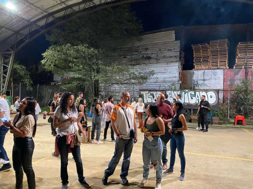 People socializing at outdoor night event with graffiti backdrop.