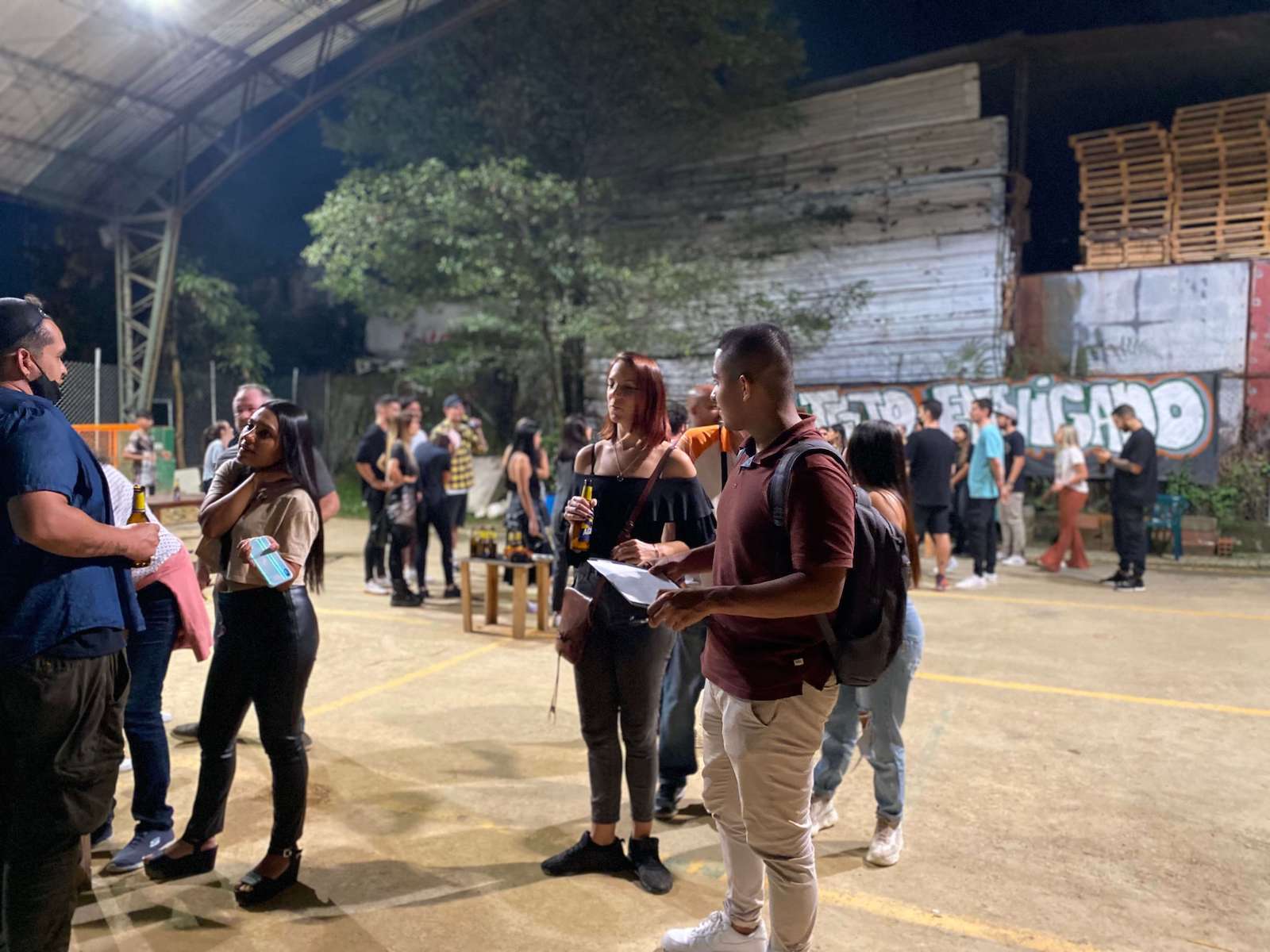 People socializing at outdoor event, night setting.